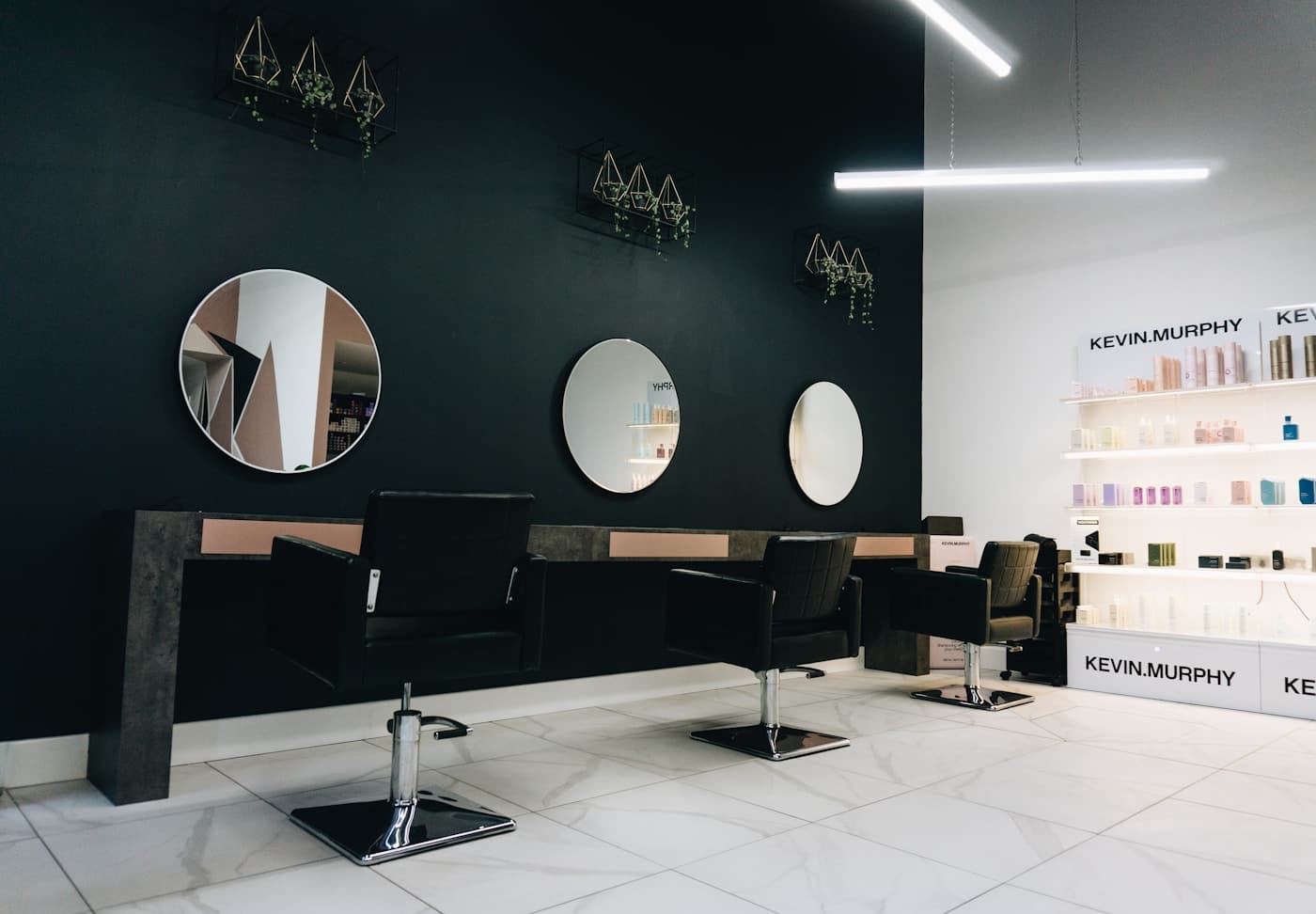 A salon with green walls, circular mirrors and styling chairs